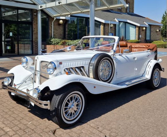 A vintage Beauford wedding car dressed with ribbons
